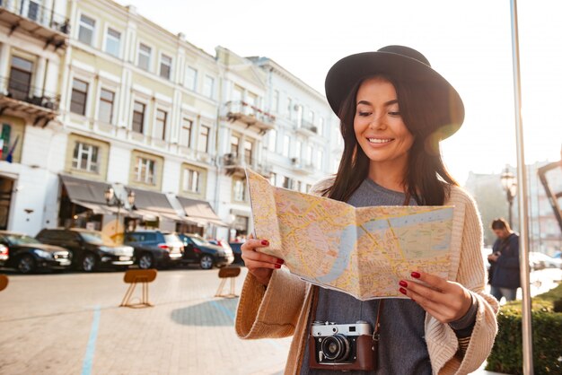 Retrato de un turista sonriente mujer sosteniendo mapa de la ciudad