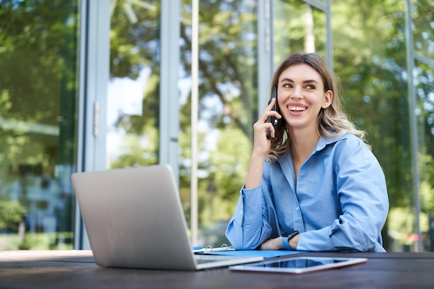 Foto gratuita retrato de una vendedora que trabaja afuera en el aire fresco cerca del edificio de oficinas mujer corporativa sonriente ingenio