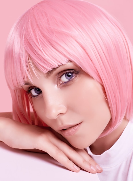 Retrato de verano brillante de una chica hermosa y positiva con cabello rosado posando en estudio colorido