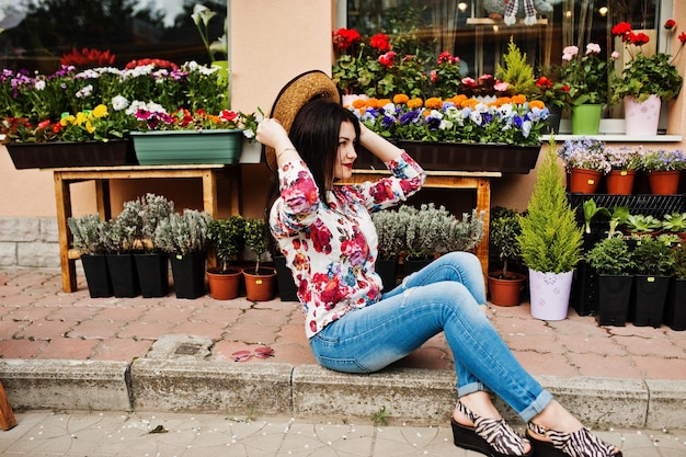 Foto gratuita retrato de verano de una chica morena con gafas rosas y sombrero contra la tienda de flores