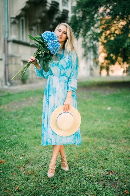 Foto gratuita retrato de verano de una hermosa mujer caminando por las calles con flores de hydragea