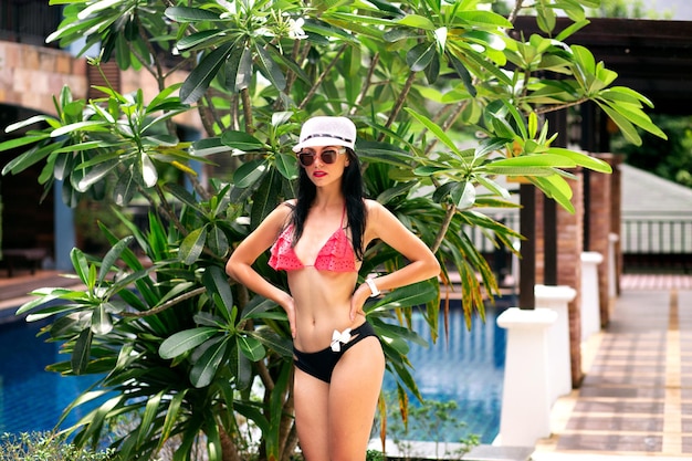 Retrato de verano de mujer morena de belleza con bikini relajarse en el hotel vacaciones en la isla tropical
