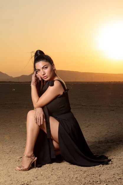 Retrato vertical de una joven caliente en el desierto al atardecer Foto de alta calidad
