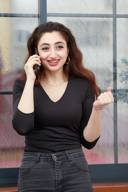 Retrato vertical de una joven hablando por teléfono y apretando el puño Foto de alta calidad
