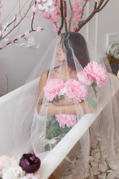 Retrato vertical de una joven sosteniendo flores de colores y mirando a un lado Foto de alta calidad