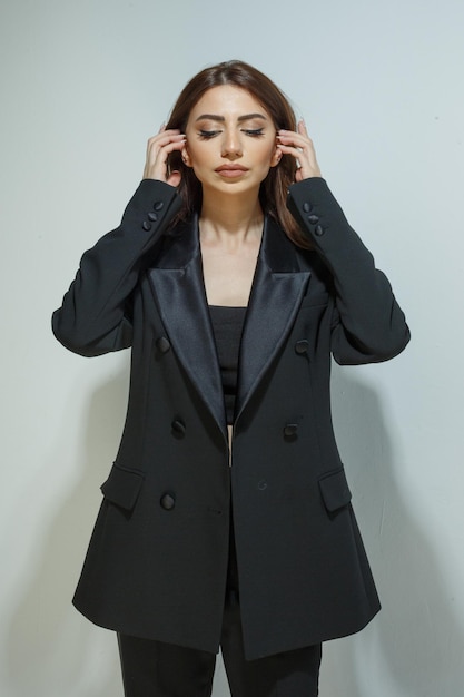 Retrato vertical de una joven con traje negro y estirando el pelo Foto de alta calidad