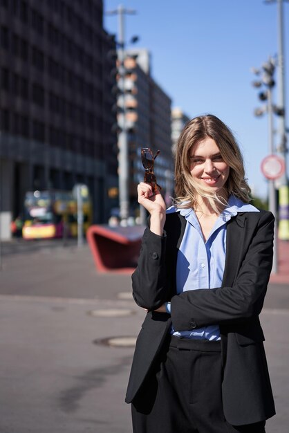 Foto gratuita retrato vertical de mujer exitosa en la calle empresaria en traje que parece confiada