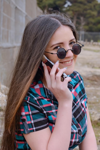 Retrato vertical de una niña sonriente hablando por teléfono