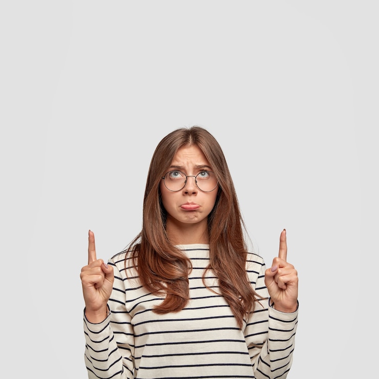 Foto gratuito retrato vertical de ofendido abusado descontento femenino europeo mira hacia arriba con disgusto, vestida con suéter blanco y negro a rayas
