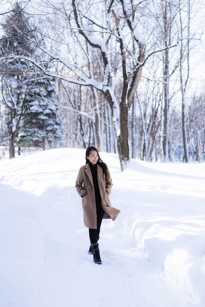 El retrato del viaje feliz de la sonrisa asiática hermosa joven de la mujer y goza con la estación del invierno de la nieve