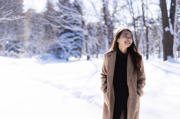 El retrato del viaje feliz de la sonrisa asiática hermosa joven de la mujer y goza con la estación del invierno de la nieve