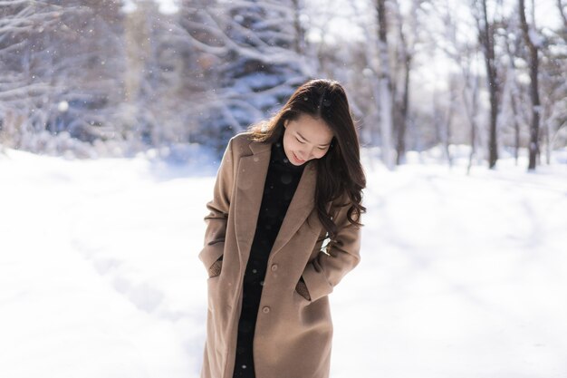 El retrato del viaje feliz de la sonrisa asiática hermosa joven de la mujer y goza con la estación del invierno de la nieve