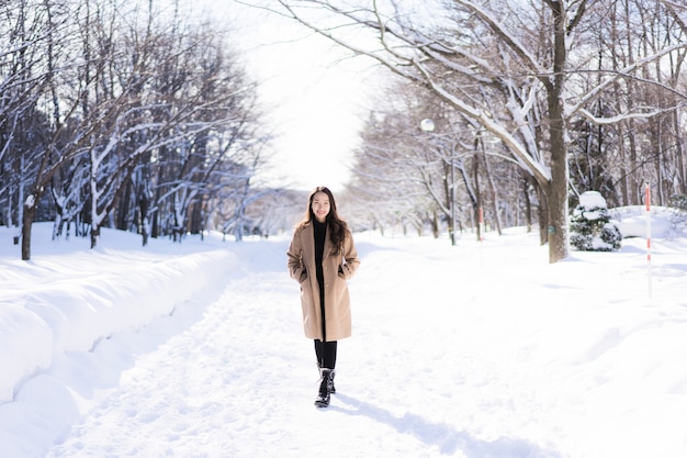 El retrato del viaje feliz de la sonrisa asiática hermosa joven de la mujer y goza con la estación del invierno de la nieve