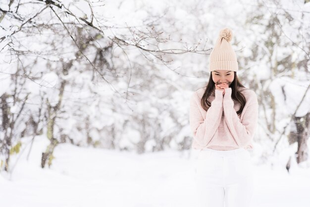 El retrato del viaje feliz de la sonrisa asiática hermosa joven de la mujer y goza con la estación del invierno de la nieve