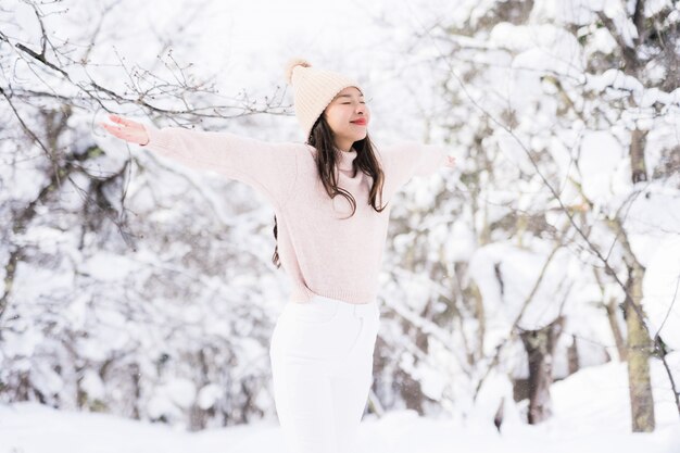 El retrato del viaje feliz de la sonrisa asiática hermosa joven de la mujer y goza con la estación del invierno de la nieve