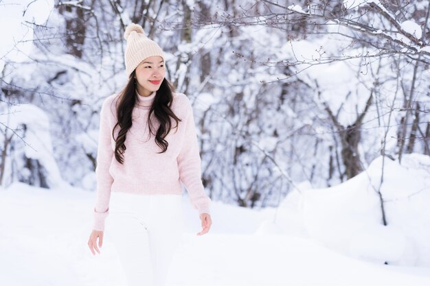 El retrato del viaje feliz de la sonrisa asiática hermosa joven de la mujer y goza con la estación del invierno de la nieve