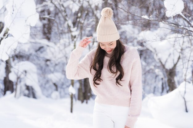 El retrato del viaje feliz de la sonrisa asiática hermosa joven de la mujer y goza con la estación del invierno de la nieve