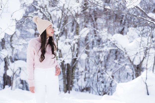 El retrato del viaje feliz de la sonrisa asiática hermosa joven de la mujer y goza con la estación del invierno de la nieve