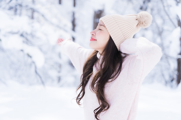 El retrato del viaje feliz de la sonrisa asiática hermosa joven de la mujer y goza con la estación del invierno de la nieve