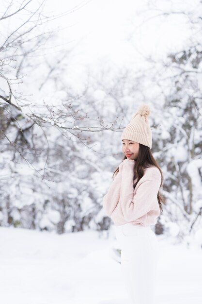 El retrato del viaje feliz de la sonrisa asiática hermosa joven de la mujer y goza con la estación del invierno de la nieve