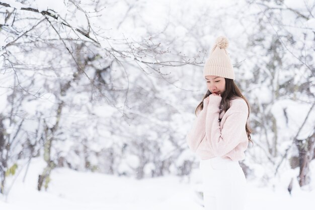 El retrato del viaje feliz de la sonrisa asiática hermosa joven de la mujer y goza con la estación del invierno de la nieve