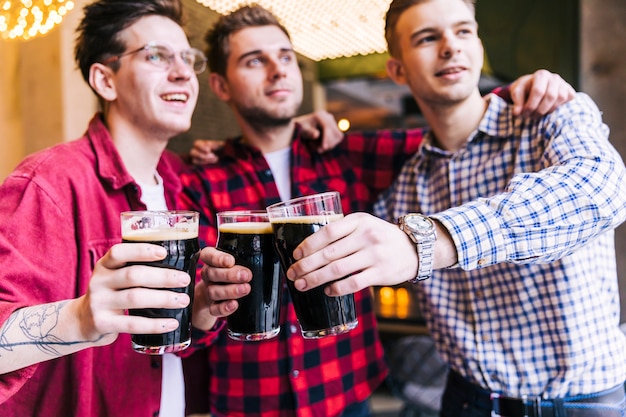 Foto gratuita retrato de los vidrios que tintinean del amigo masculino con la cerveza en pub