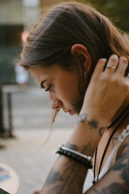 Foto gratuita retrato de vista lateral de mujer joven en la calle, mirando hacia abajo