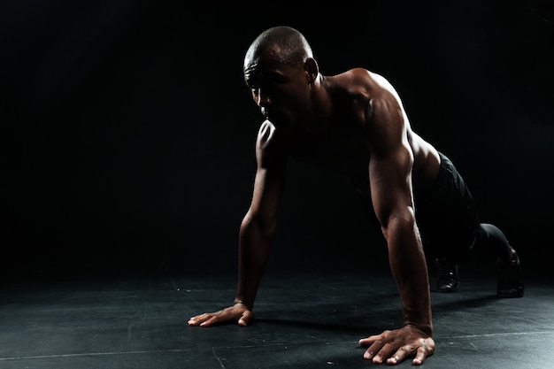 Retrato de youg afroamericano deportista haciendo ejercicio de flexiones