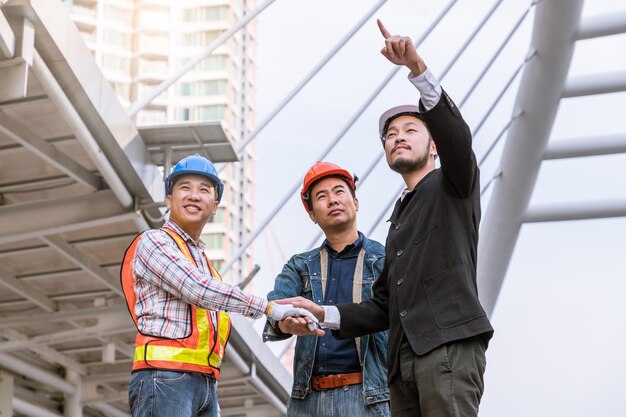 Reunión del gerente con el ingeniero en la mano de la pila del sitio al aire libre para el trabajo en equipo