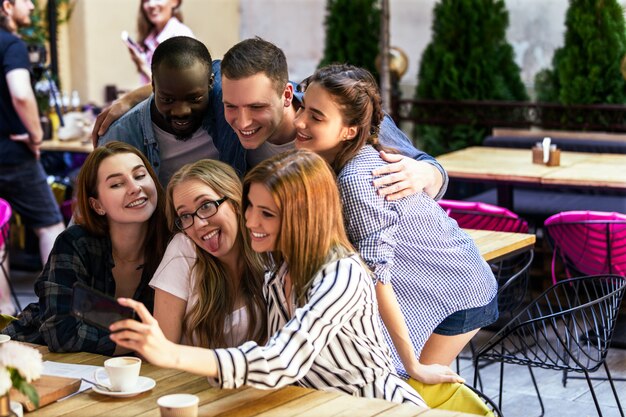 Reunión informal de los mejores amigos en el acogedor café y tomar una foto selfie en el teléfono inteligente