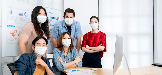 Reunión de lluvia de ideas multirracial de inicio de pequeñas empresas asiáticas con computadora portátil y papel cuadriculado para todos enmascarados para la protección covid19 gripe corona prevenir ideas saludables concepto fondo de oficina