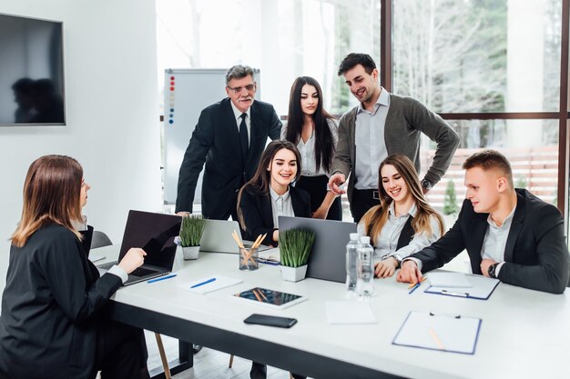 Reunión de personal. Grupo de jóvenes modernos en ropa casual elegante discutiendo algo mientras trabaja en la oficina creativa. Tiempo de Negocios.