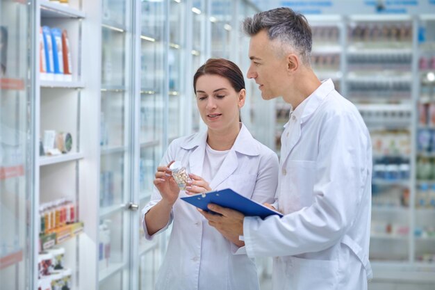 Revisión. Dos farmacéuticos haciendo revisión de medicamentos en una farmacia.