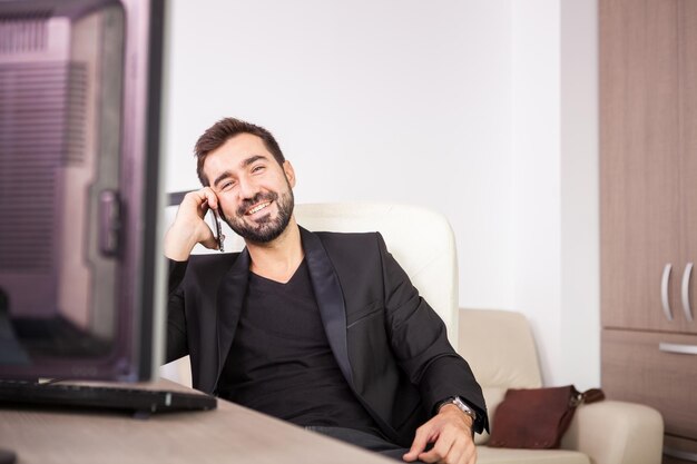 Riendo a empresario hablando por teléfono mientras trabajaba en su oficina. Empresario en entorno profesional