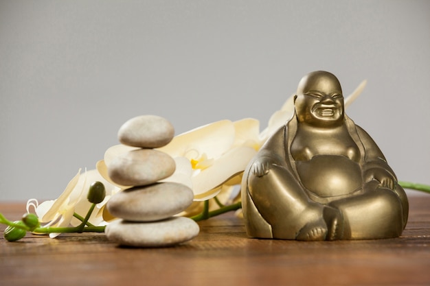 Riendo figurilla de Buda con los guijarros de piedra y la flor