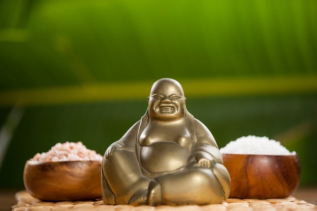 Riendo figurilla de Buda y la sal del mar en un tazón de madera