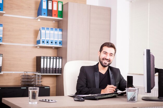 Riendo a hombre de negocios profesional que trabaja en su oficina. Empresario en entorno profesional