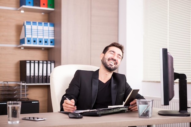 Riendo a hombre de negocios profesional que trabaja en su oficina. Empresario en entorno profesional