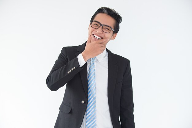 Riendo joven empresario asiático tocar la barbilla