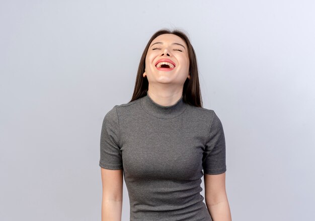 Riendo a una mujer bonita joven con los ojos cerrados aislado sobre fondo blanco con espacio de copia