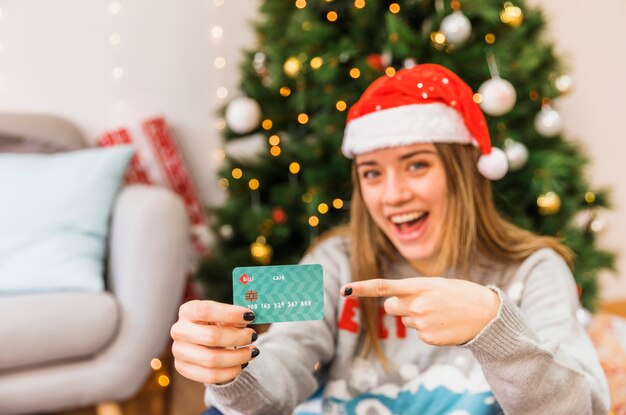 Riendo a mujer festiva apuntando a tarjeta de crédito