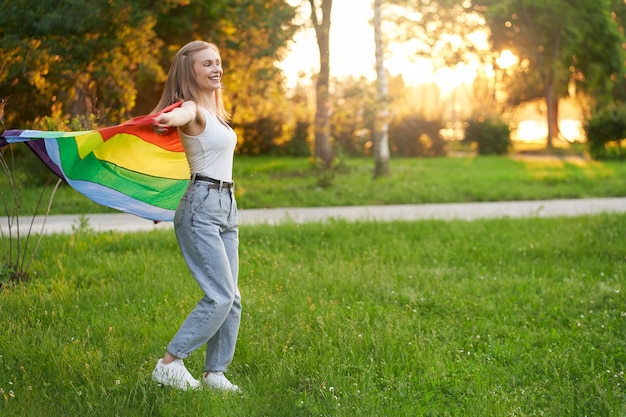Riendo mujer tolerante bailando con bandera lgbt arco iris