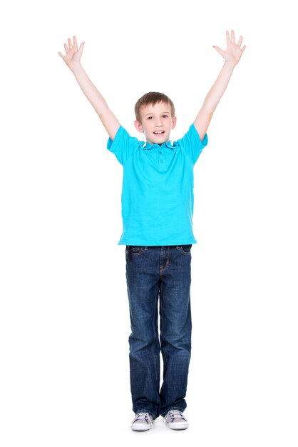 Riendo a niño feliz con las manos levantadas en una camiseta azul, aislada sobre fondo blanco.