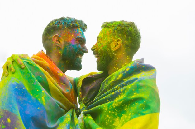 Riendo a los novios gay desordenados abrazándose en el desfile del orgullo