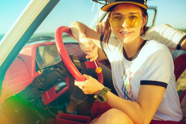 Riendo pareja romántica sentada en el coche mientras está en un viaje por carretera en verano