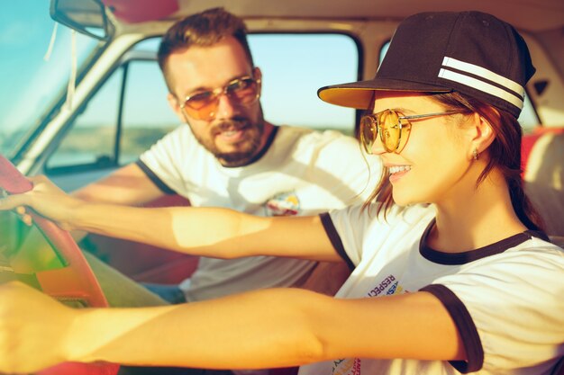 Riendo pareja romántica sentada en el coche mientras está de viaje por carretera