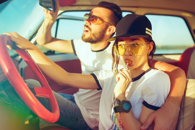 Riendo pareja romántica sentada en el coche mientras está de viaje por carretera