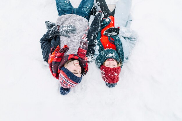 Riendo pareja romántica tumbado en la nieve