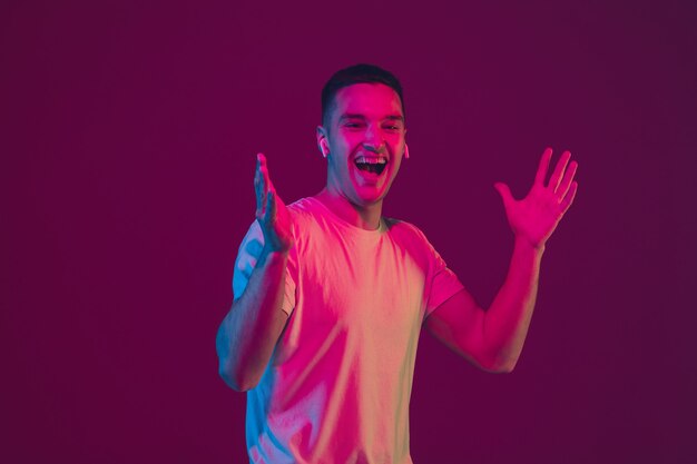 Riendo, sorprendido. Retrato de hombre caucásico aislado en la pared del estudio de color rosa-violeta.