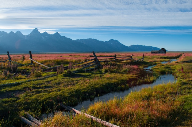 Foto gratuita río en medio de un campo verde rodeado de un paisaje montañoso.